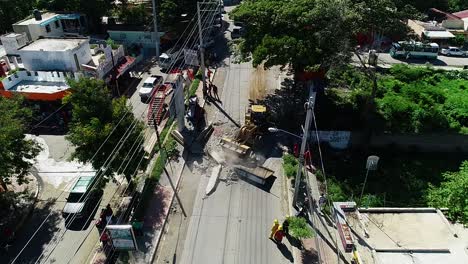 aerial view of a machine and crew repairing hurricane aftermath, on city streets - descending, drone shot