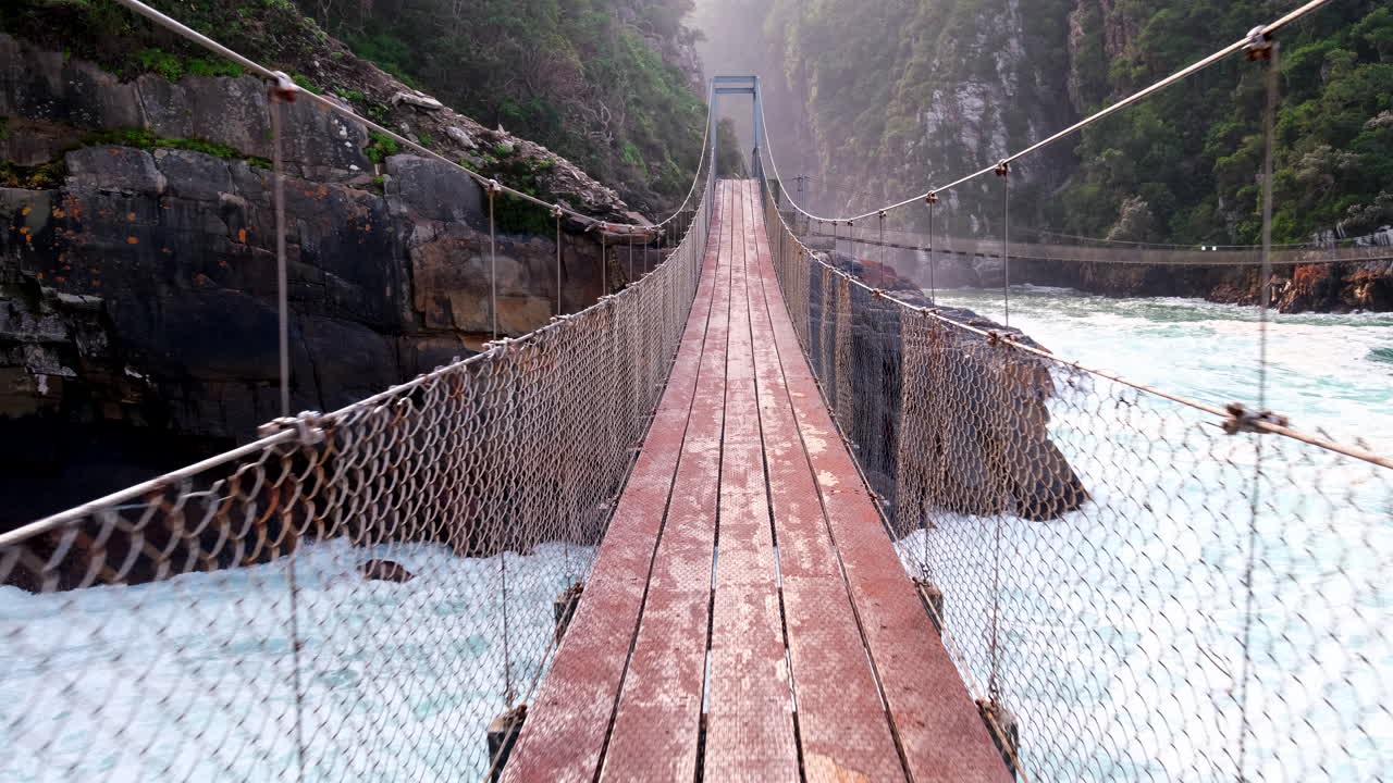 Thrilling POV walking on Storms River suspension bridge over crashing waves