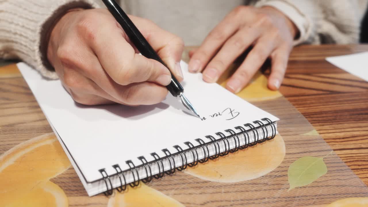 Hands writing in notebook with pen on wooden table