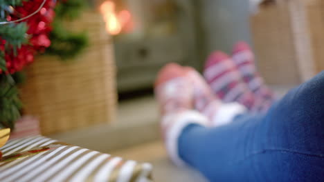 christmas gifts and feet of couple in warm socks by fireplace, copy space, slow motion