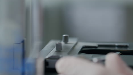close-up of scientist positioning glass slide on microscope stage