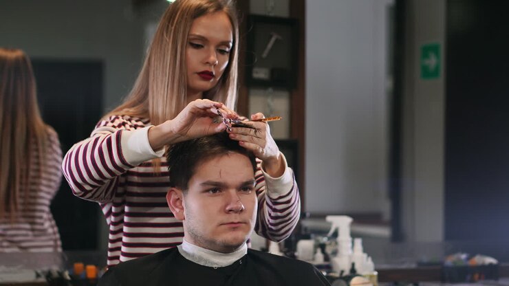 Una parrucchiera che taglia i capelli a un cliente uomo sorridente in un salone di bellezza.