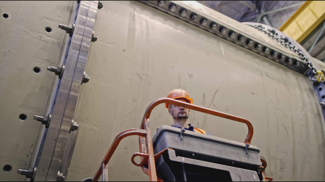trabajador en el ascensor inspeccionando un gran tanque industrial