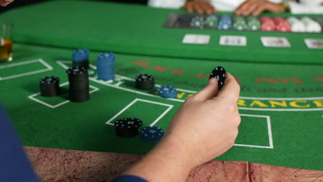 a man playing with poker chip in a casino at a black jack table