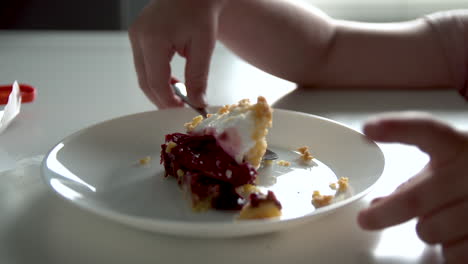 hände des babys, die versuchen, den löffel vom tisch zu nehmen, um leckeres stück kuchen zu essen