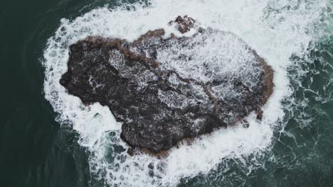 Tomada-Desde-Un-Dron-Sobre-Una-Formación-Rocosa-En-El-Mar,-En-La-Que-Chocan-Las-Olas.