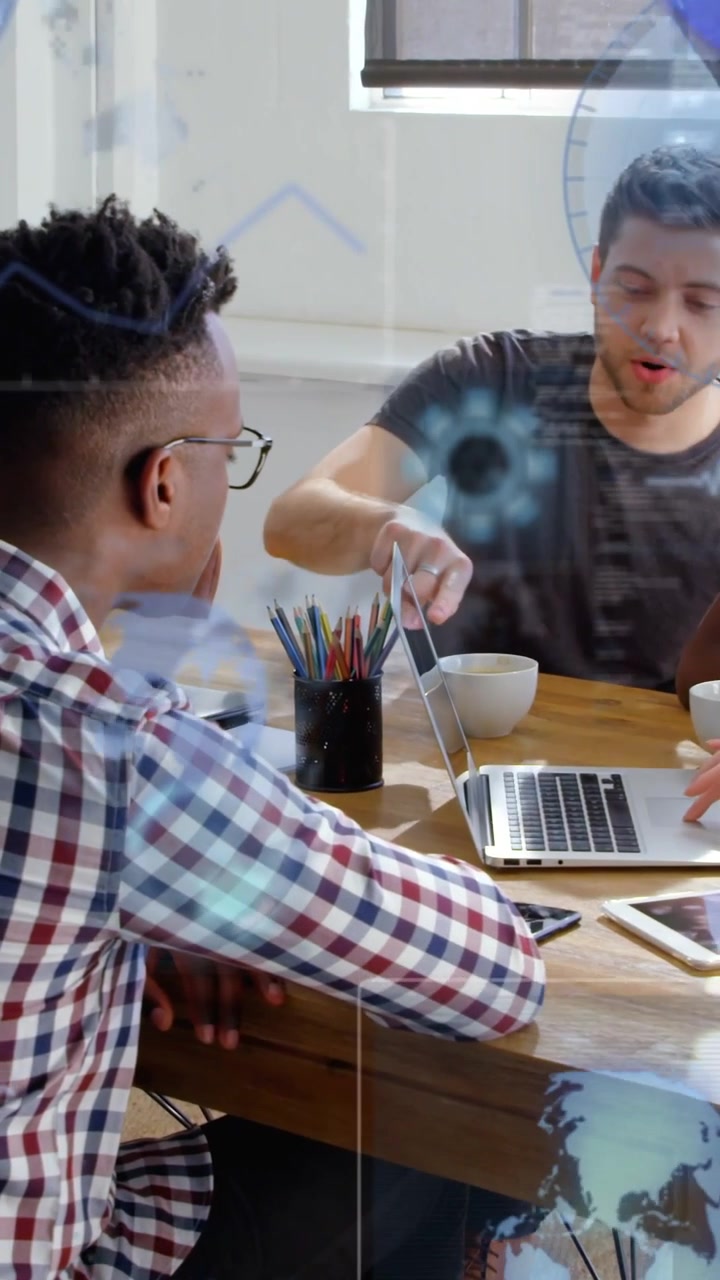 Video verticale: Uomo in maglietta grigia che indica un laptop e genera grafici tecnologici blu per la revisione del progetto.