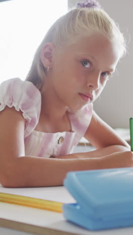 video of focused caucasian girl sitting at desk in classsroom