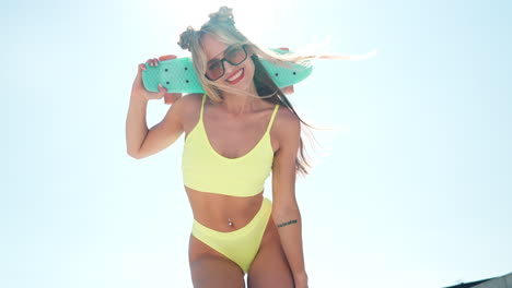 mujer en traje de baño amarillo con patineta
