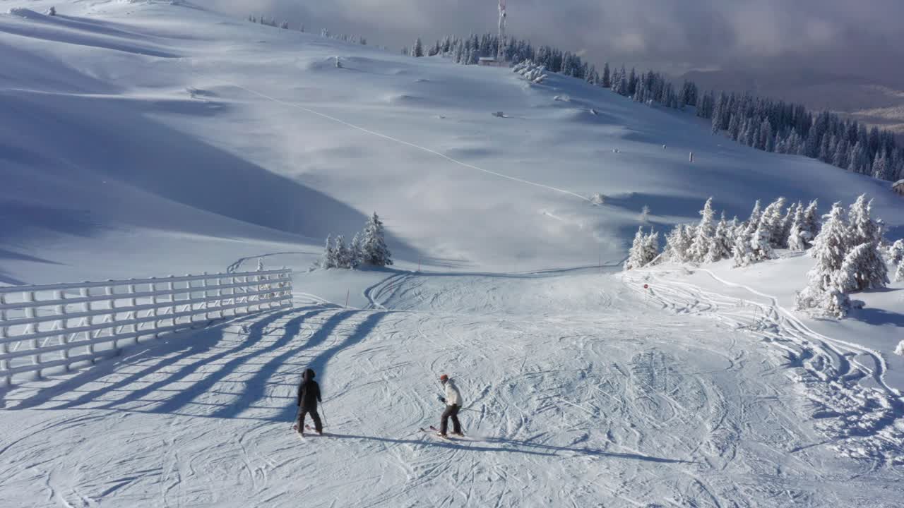 Beginner skiers falling over on mountain ski resort ski slopes, 4K aerial view