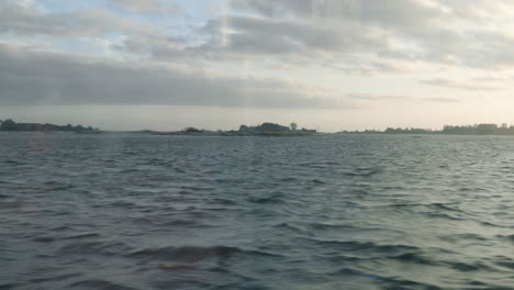 Window-shot-inside-a-ferry-passing-by-Suomenlinna-island,-on-a-autumn-day,-in-Helsinki,-Uusimaa,-Finland