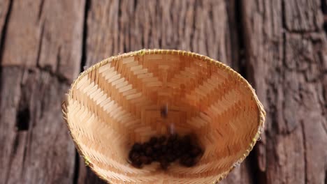 coffee beans peaberry small size picking falling bamboo basket log wooden background. selective focus on foreground with copy space.