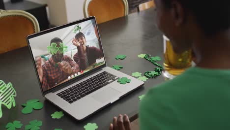 pareja sonriente y diversa que usa artículos en forma de trébol en una videollamada en una computadora portátil