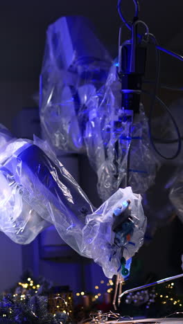 moving robotic hands covered in plastic. innovative equipment working in dark surgery room with christmas decorations. vertical video