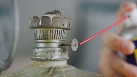 pulverización de lubricante en la perilla de una vieja lámpara de aceite