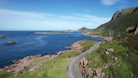 Dangerous-coastal-gravel-road-to-a-historical-fishing-village,-aerial-forwarding-shot