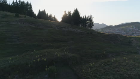 aerial: flying near a hill behind which the sun rises and there is a small village