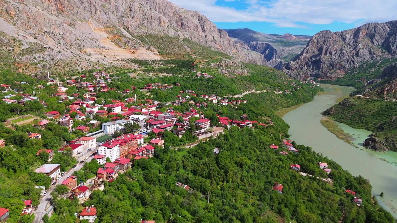 Vid flygvy över staden Kemaliye och den slingrande floden Eufrat som flyter genom en djup dal. Pittoreskt bergslandskap, traditionella röda takhus och grön natur i Turkiet.