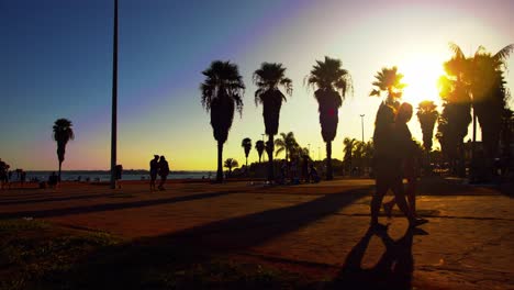 Silhouette-of-people-walking-on-ocean-side-broadwalk-during-sunset-in-Brasilia,-Brazil