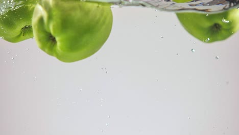 green apples splashing in water