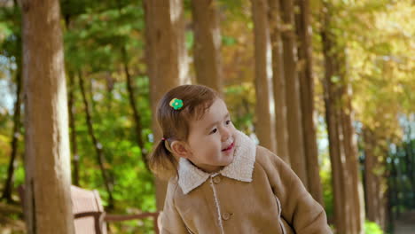 preschool child jumping in a scenic autumn metasequoia alley park in slow motion lit with warm sunlight