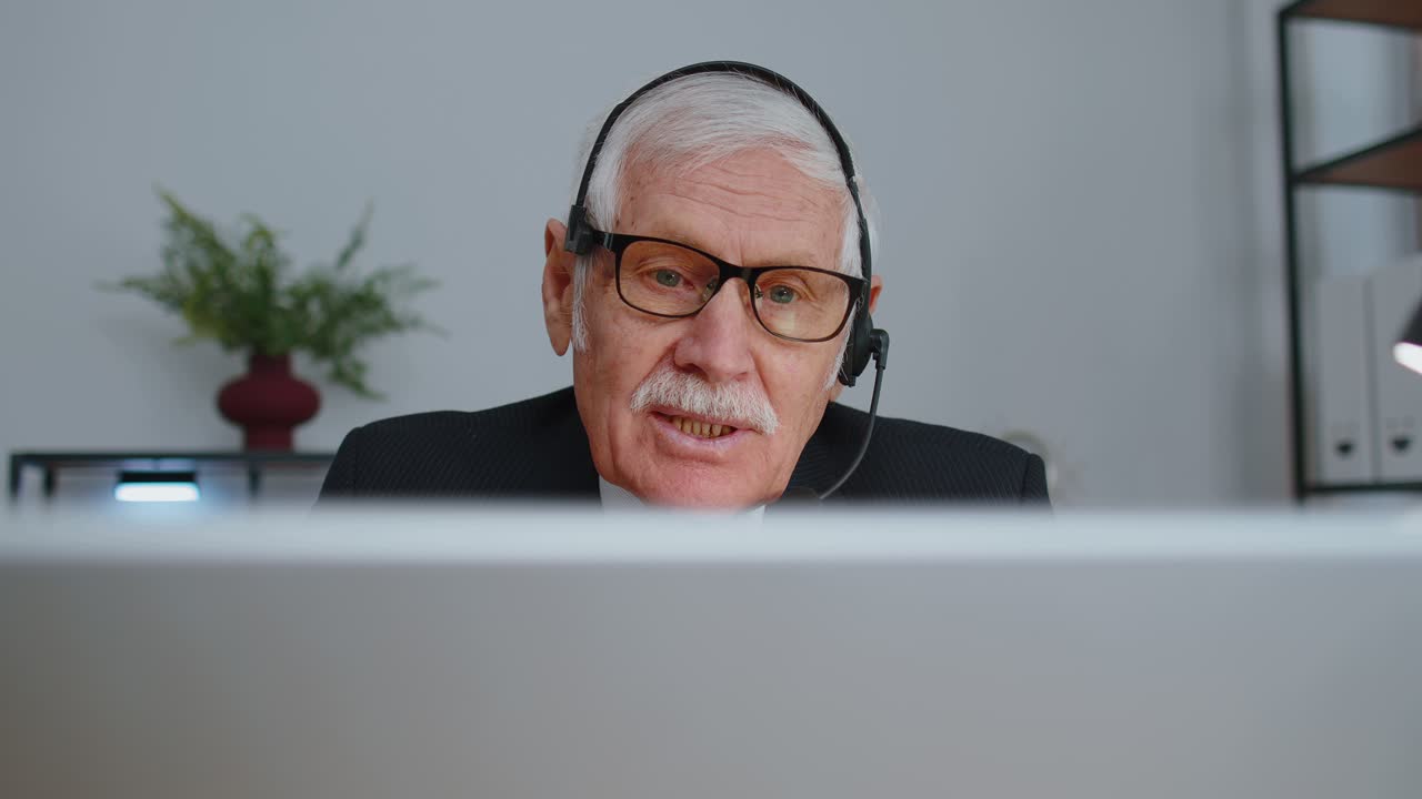 Ældre forretningsmand med headset, der arbejder i et kontormødecenter som supportmedarbejder
