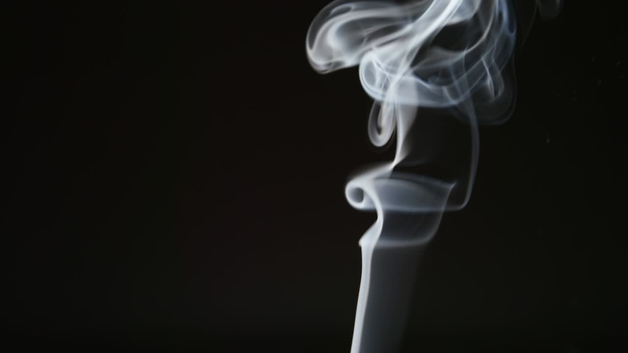 SLOW MOTION: Curly steam of smoke on a black background