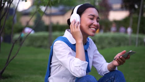 cheerful woman listening to music with headphones and phone outdoors