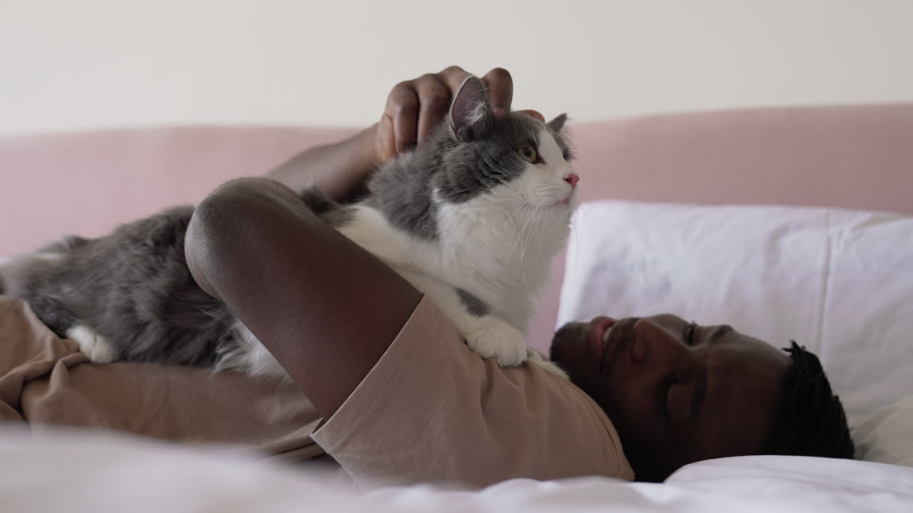 Pet owner with his cat on bed