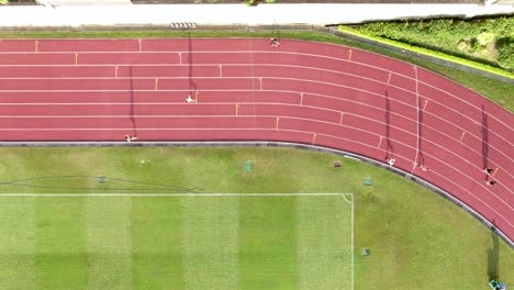 gente durante la mañana trotando en una pista de carreras con largas siluetas almidonadas, vista aérea