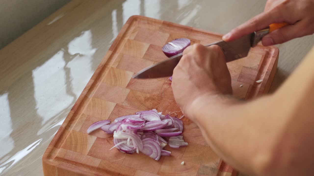 Person's Hand Slicing Red Onion On Wooden Chopping Board. - closeup shot