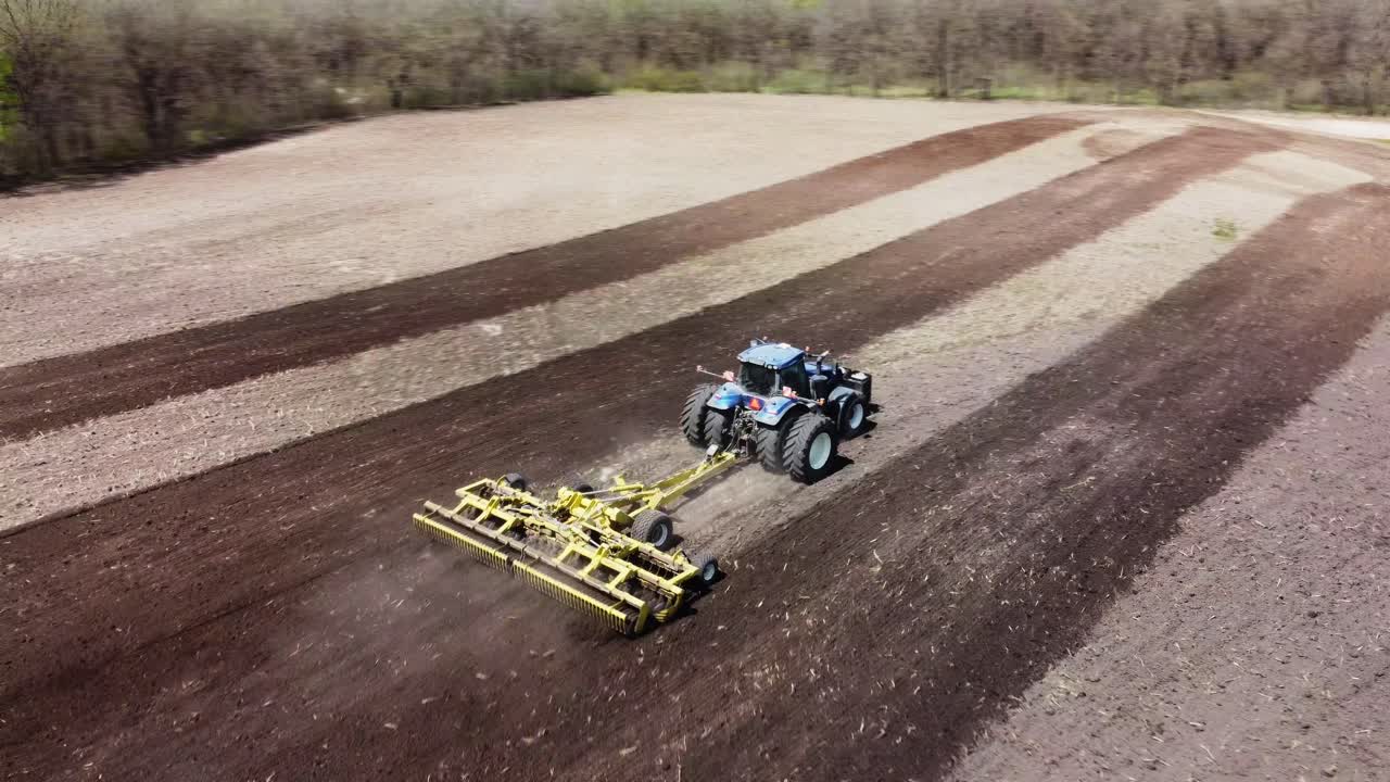 Aerial swing around video of a tractor plow tilling a field