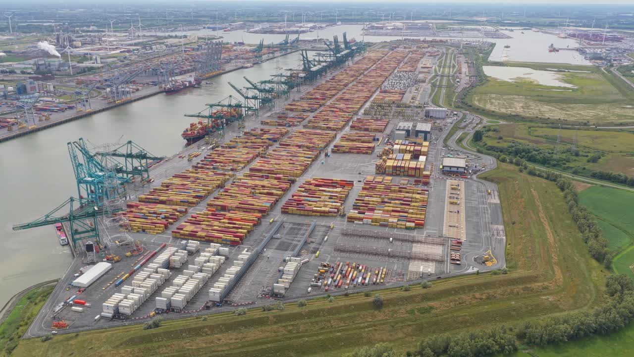 Aerial drone view of Antwerp port cranes unloading vessels at container docks, Belgium