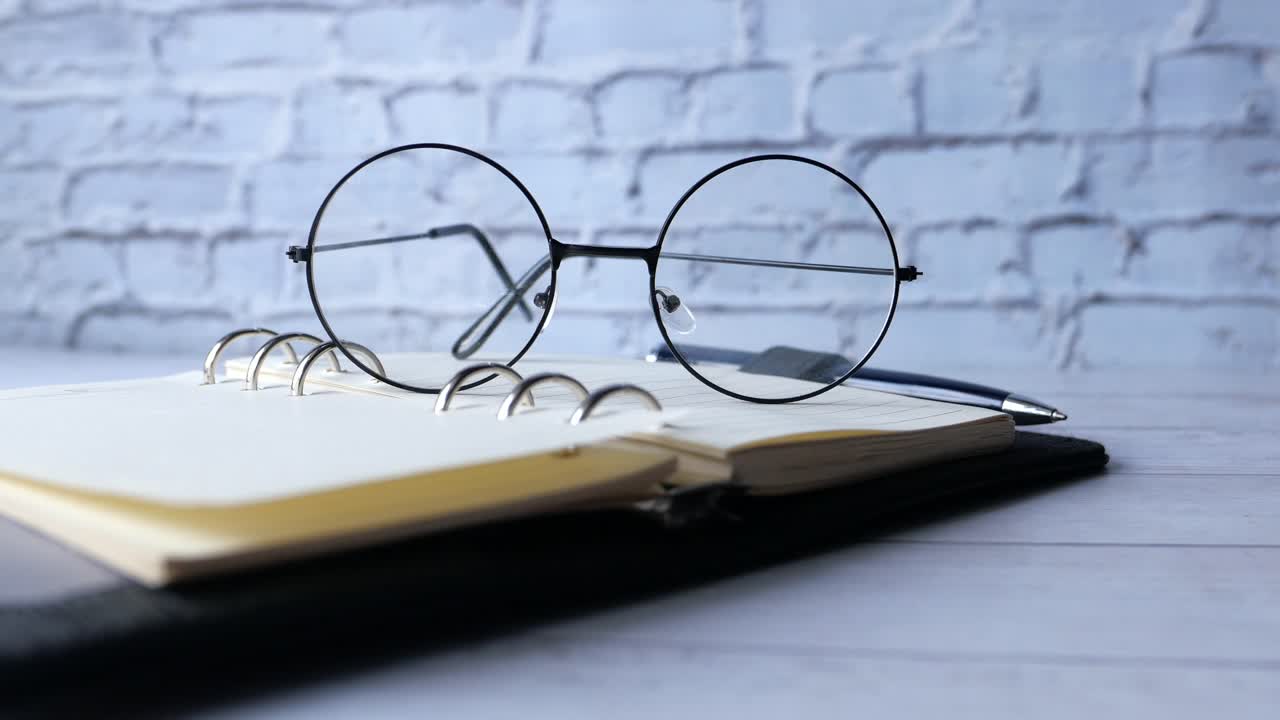 cuaderno abierto con gafas y bolígrafo