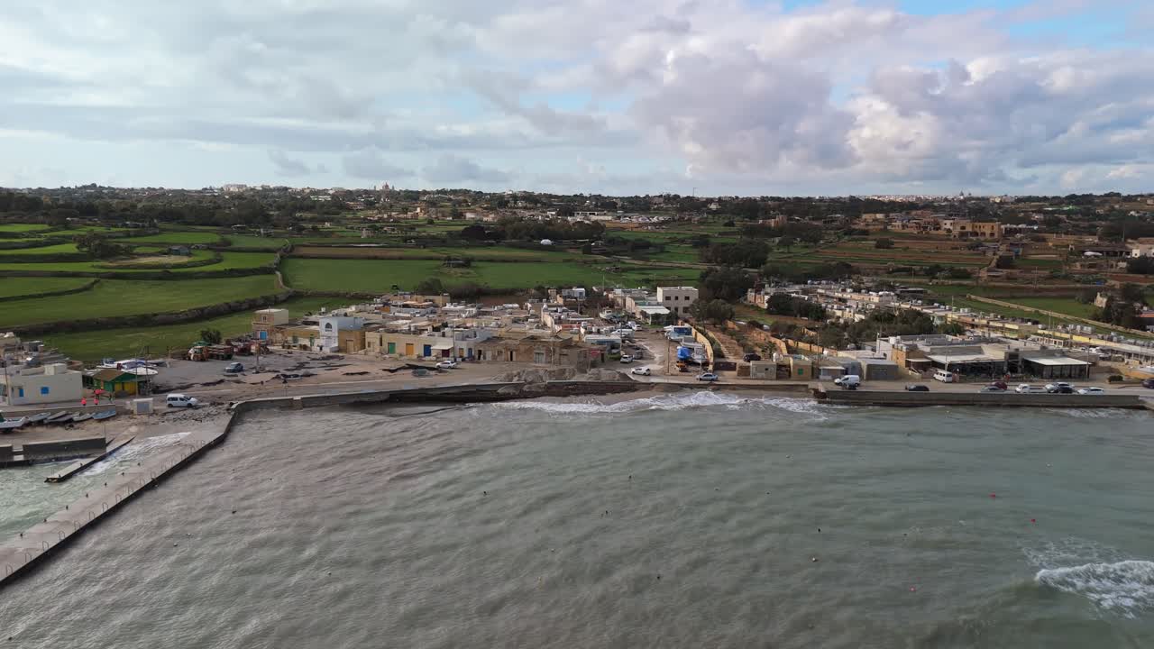 Droneoptagelse i sidelæns sporing af de mudrede veje efter cyklonen Harry langs kystlinjen ved St. Thomas Bugt i Marsaskala, Malta, mens det bølgede Middelhav stormer kysten.