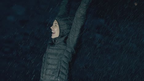 mujer joven con chaqueta verde sonríe y disfruta de la lluvia torrencial