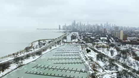 aerial descent on boat harbor with downtown chicago in background during cold winter day