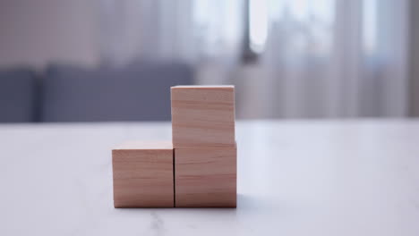 tomando un primer plano de un individuo apilando bloques de madera uno encima del otro en una mesa