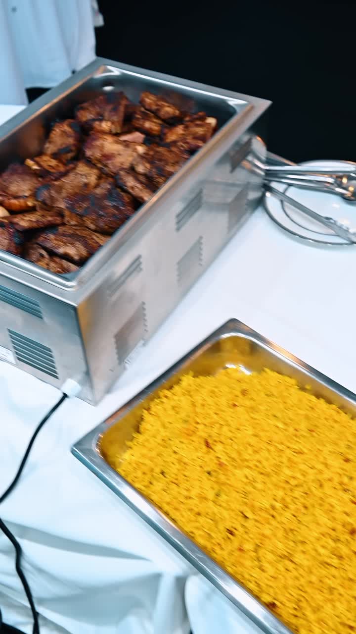 Tavolo da buffet con piatti di pasta e riso con verdure. Vista dall'alto di una linea di buffet che presenta penne al pesto, penne al pomodoro e riso giallo con verdure miste in vassoi.