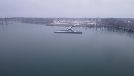 Huge-pier-in-the-Detroit-River-International-Wildlife-Refuge-Humbug-Marsh-Unit-on-Detroit-river-covered-in-snow-on-moody-winter-day,-aerial-view