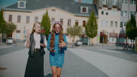 two women walking and talking in a city square