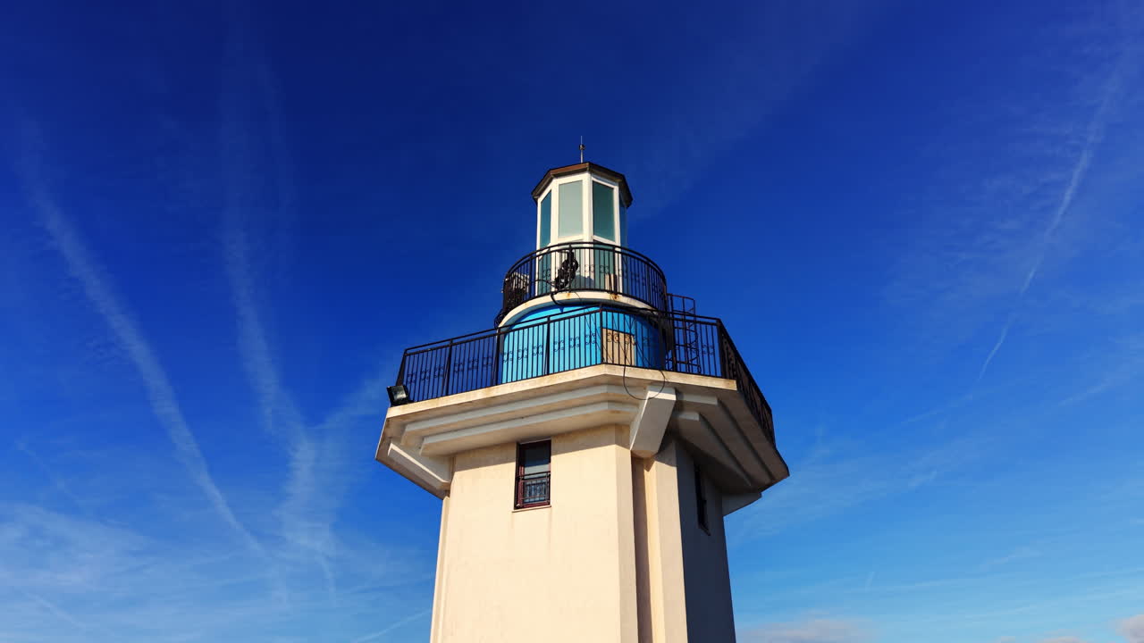 Faro in cemento bianco con sezione superiore blu e una piccola finestra su un cielo blu scuro limpido. Bulgaria