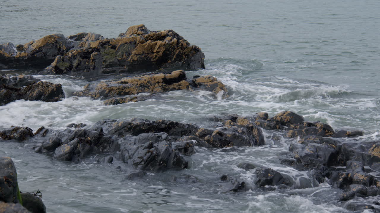Shot of waves breaking over rocks are low tide at Tresaith beach