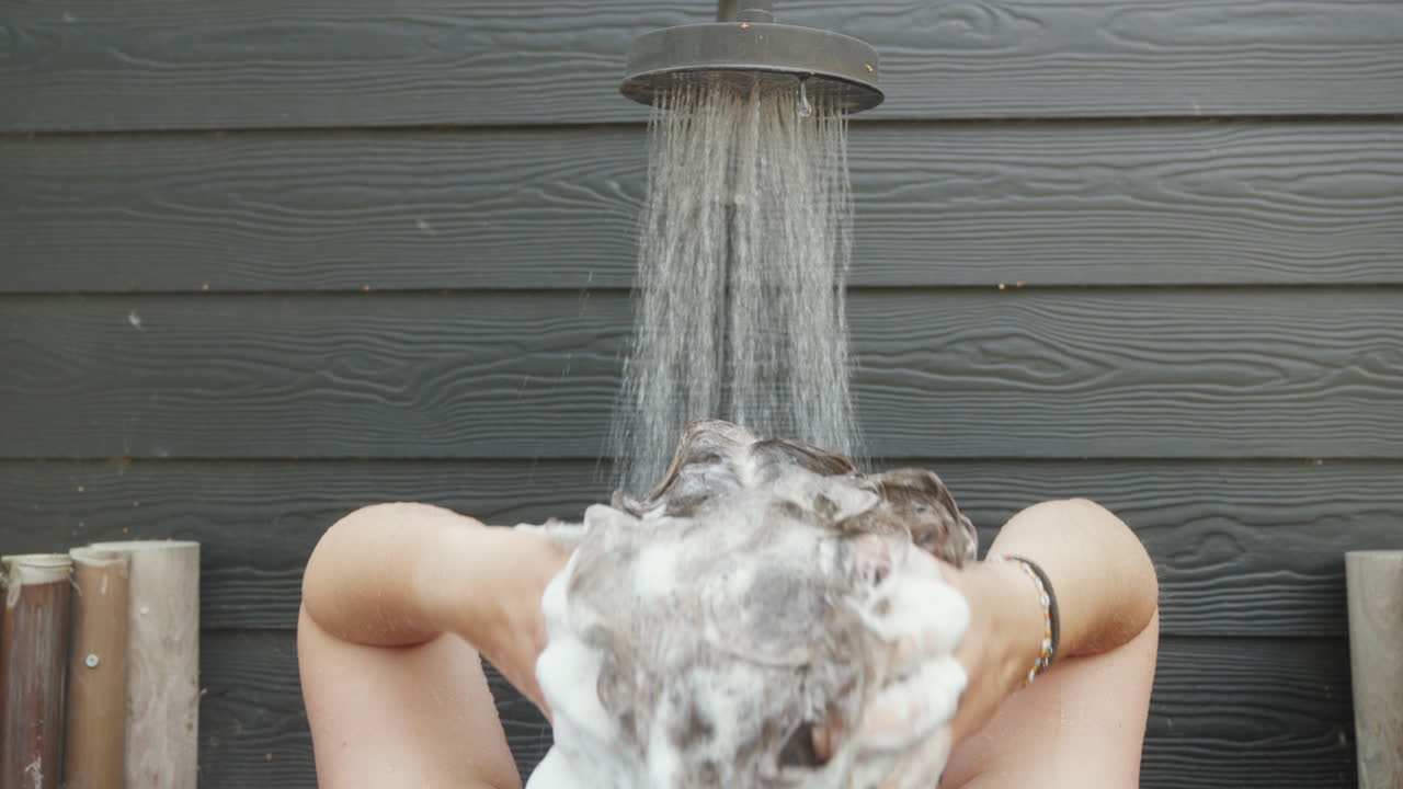 Person enjoying refreshing outdoor shower. Ideal for travel and lifestyle promotions.