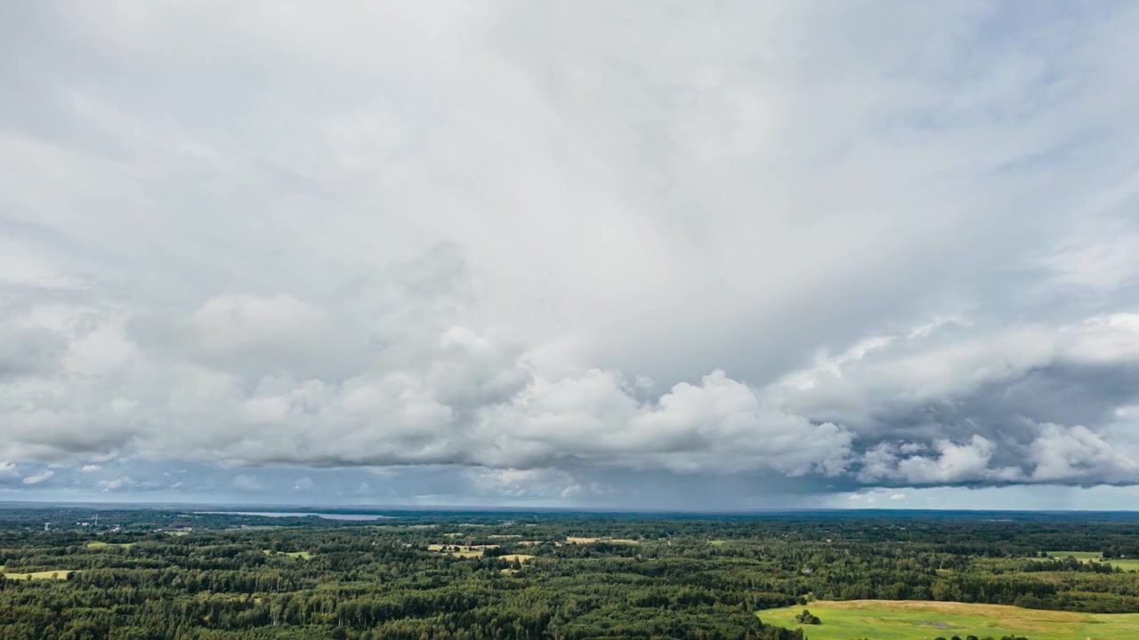 Hyperlapse aereo di nuvole di pioggia drammatiche e un fronte temporalesco che si muove su un paesaggio rurale verde.