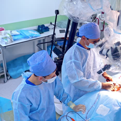 complicated surgery through the microscope. medical team in blue uniform perform operation in a modern operating room.
