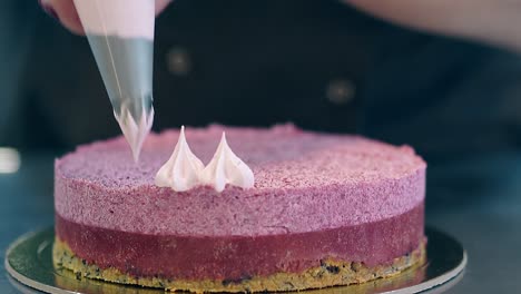 confectioner decorates pink biscuit cake using pastry bag