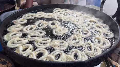 a man preparing fresh hot jalebi in a road side stall in india