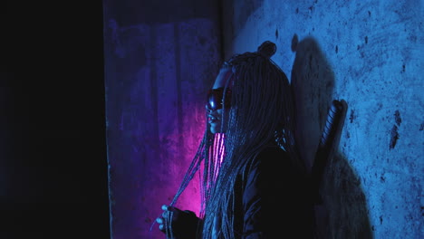 una chica con dreadlocks y katanas está de pie junto a una pared de ladrillo de neón masticando chicle