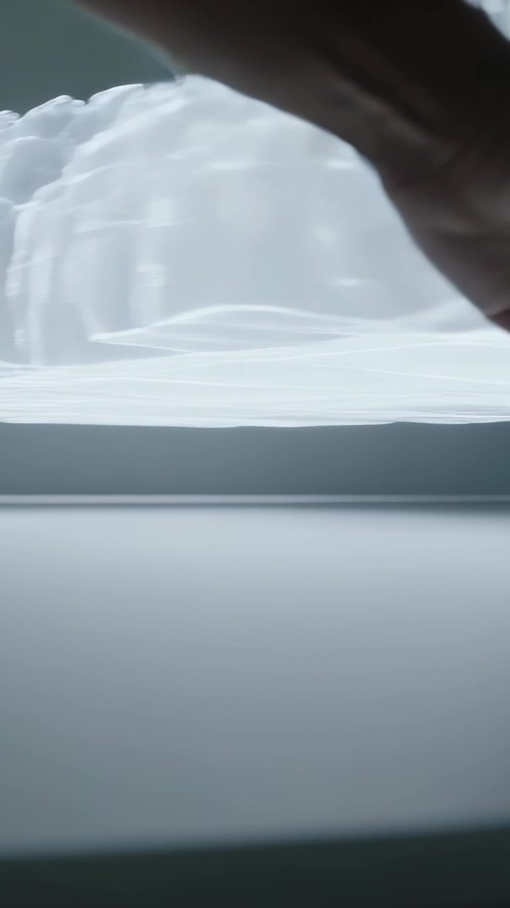 Video verticale: Mano che scorre entrando da sinistra su uno strato olografico che si estende su un tavolo da studio esplorando un modello 3D